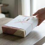 上品な和紙で包装されたお中元のギフトボックスと、それに優しく触れる手。